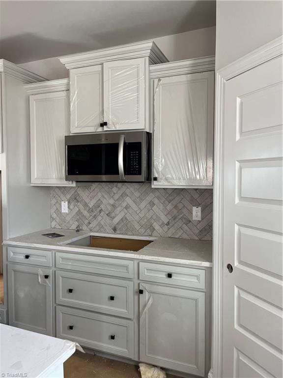 kitchen with white cabinetry, black electric stovetop, and backsplash