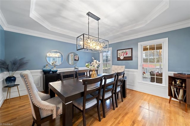 dining room featuring a tray ceiling, a wainscoted wall, and light wood finished floors