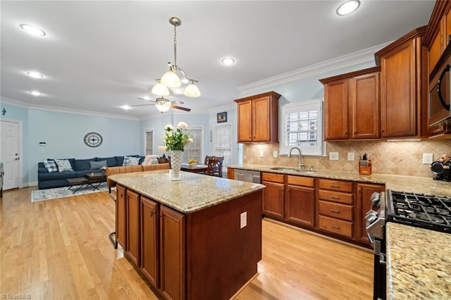 kitchen featuring a sink, light wood-type flooring, a kitchen island, and appliances with stainless steel finishes