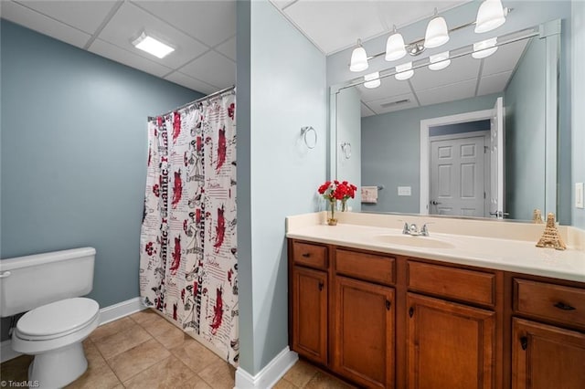 bathroom with vanity, toilet, tile patterned flooring, and a drop ceiling