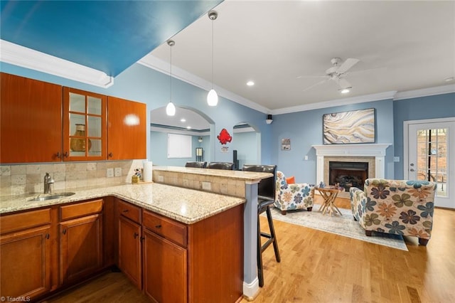 kitchen with arched walkways, open floor plan, a peninsula, and a sink