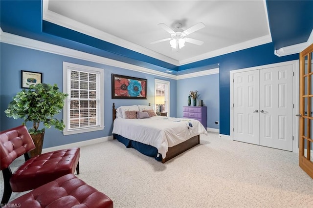 carpeted bedroom with a closet, a ceiling fan, crown molding, and baseboards