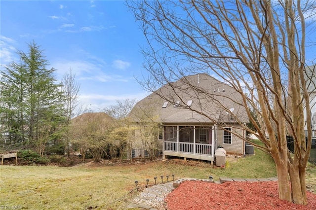 back of house with a yard, a shingled roof, and a sunroom