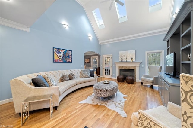 living room featuring crown molding, wood finished floors, arched walkways, and a premium fireplace