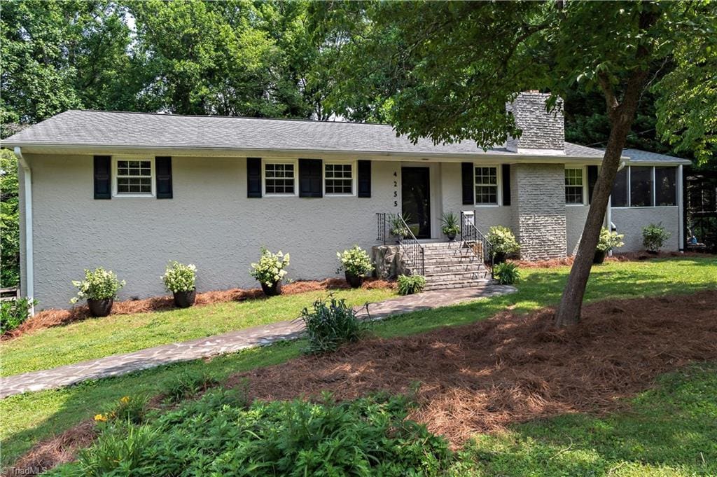 4255 Bower Ln, Winston-Salem, NC 27104 - ranch-style home with a chimney, a sunroom, a front lawn, and stucco siding