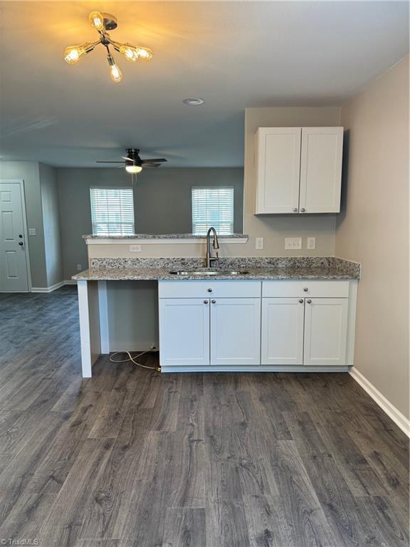 kitchen with a wealth of natural light, sink, light stone counters, and white cabinets