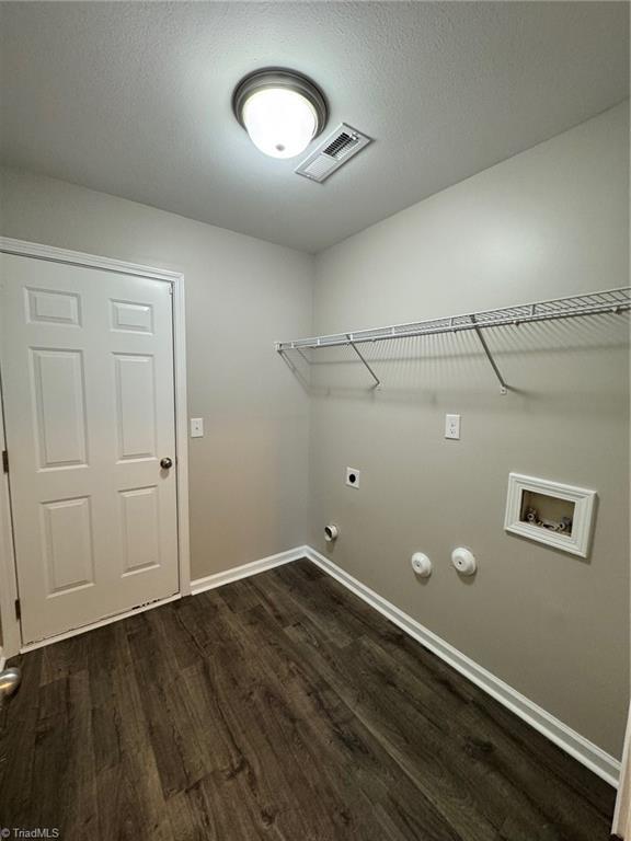 laundry room with hookup for a washing machine, hookup for a gas dryer, electric dryer hookup, a textured ceiling, and dark hardwood / wood-style floors