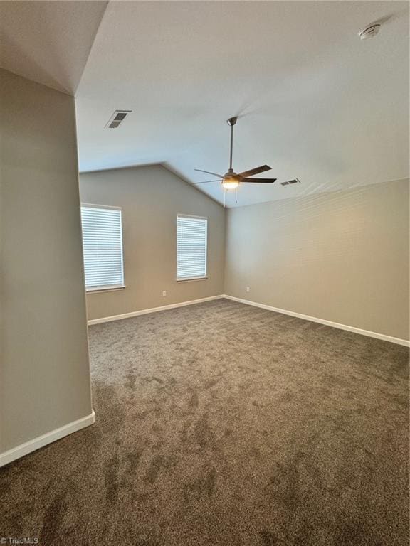 spare room featuring dark carpet, ceiling fan, and vaulted ceiling