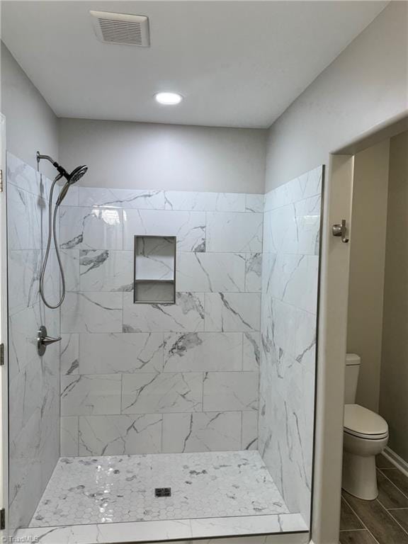 bathroom with a tile shower and toilet