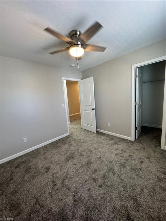 unfurnished bedroom featuring carpet, a spacious closet, and ceiling fan