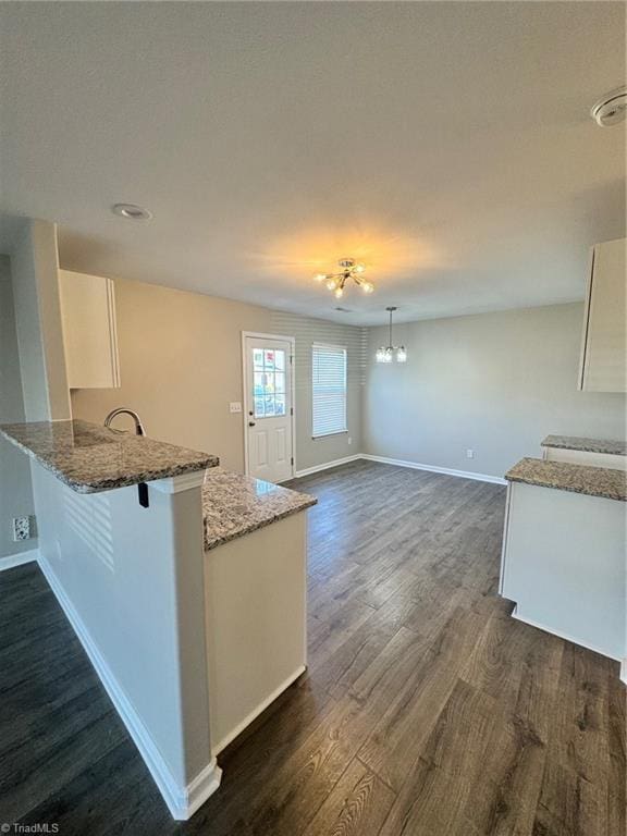 kitchen featuring kitchen peninsula, dark hardwood / wood-style floors, hanging light fixtures, and white cabinets