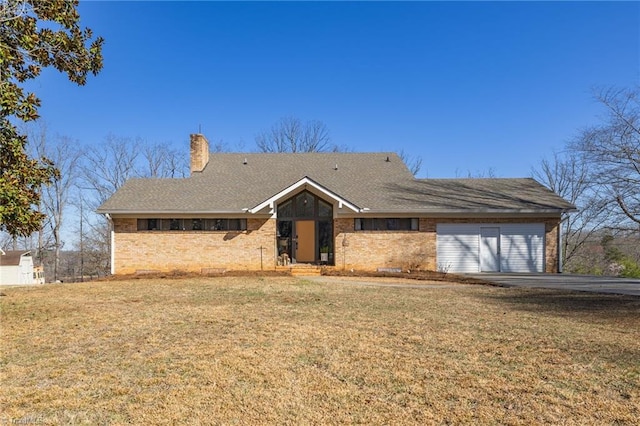 view of front of home with brick siding, a garage, a front yard, and a chimney