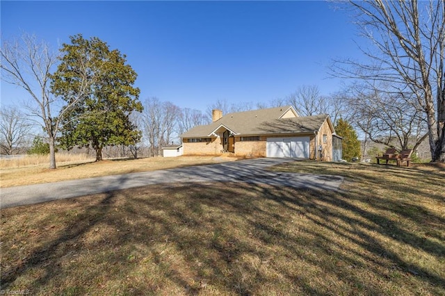 view of front of property featuring an attached garage, driveway, a chimney, and a front yard