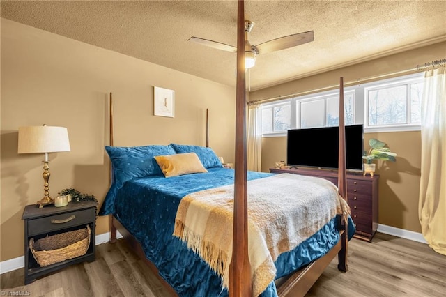 bedroom featuring a ceiling fan, wood finished floors, baseboards, and a textured ceiling