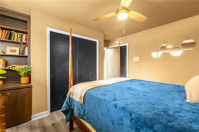 bedroom featuring baseboards, a textured ceiling, a ceiling fan, and wood finished floors