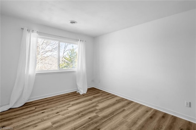 unfurnished room featuring visible vents, baseboards, and wood finished floors