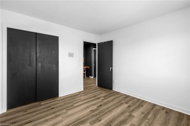 unfurnished bedroom featuring a closet, baseboards, and wood finished floors