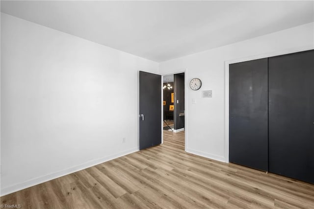 unfurnished bedroom featuring light wood-style flooring, baseboards, and a closet