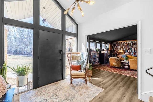 entryway featuring a chandelier, lofted ceiling, and wood finished floors