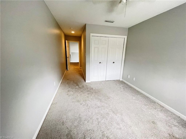 unfurnished bedroom featuring light carpet, a closet, and ceiling fan