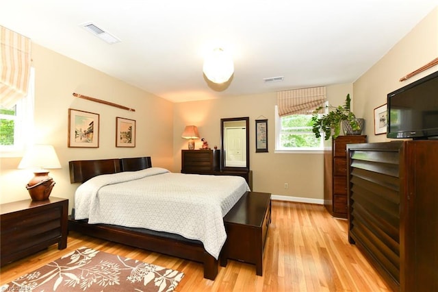 bedroom featuring visible vents, light wood-style flooring, and baseboards