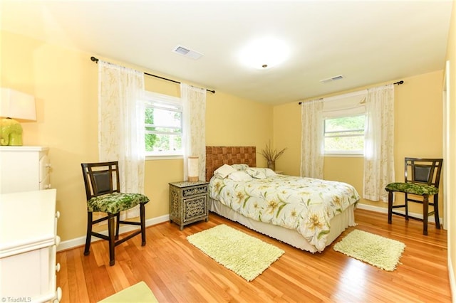 bedroom with multiple windows, wood finished floors, and visible vents