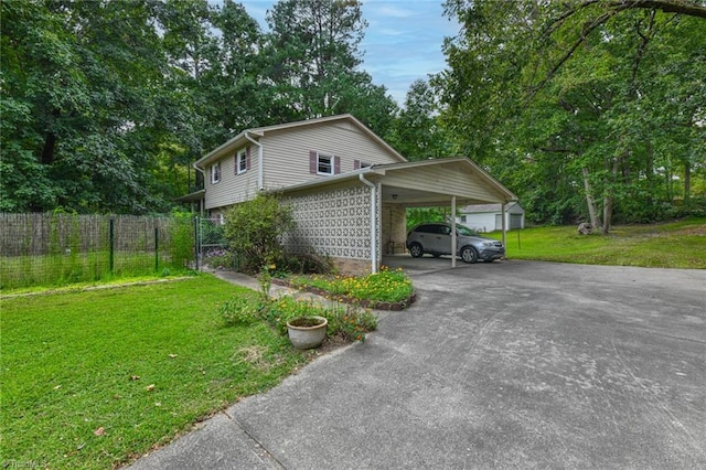 view of side of home featuring aphalt driveway, an attached carport, a yard, and fence