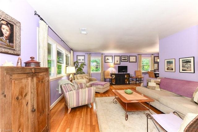 living room featuring baseboards, a healthy amount of sunlight, and light wood-style flooring