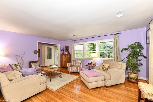 living room featuring visible vents, baseboards, and light wood finished floors