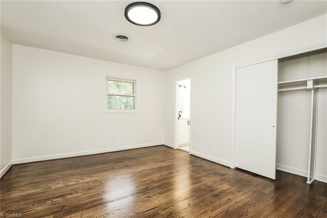 unfurnished bedroom featuring a closet and dark wood-type flooring