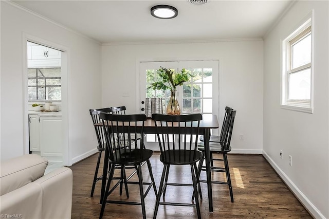 dining room featuring ornamental molding, a wealth of natural light, and dark wood-type flooring