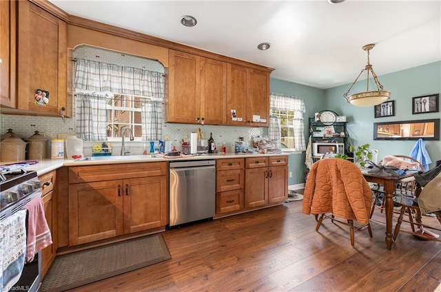 kitchen featuring brown cabinetry, dark wood-style floors, stainless steel appliances, and a sink