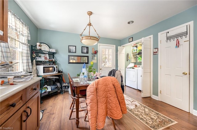 dining area featuring independent washer and dryer, wood finished floors, and baseboards