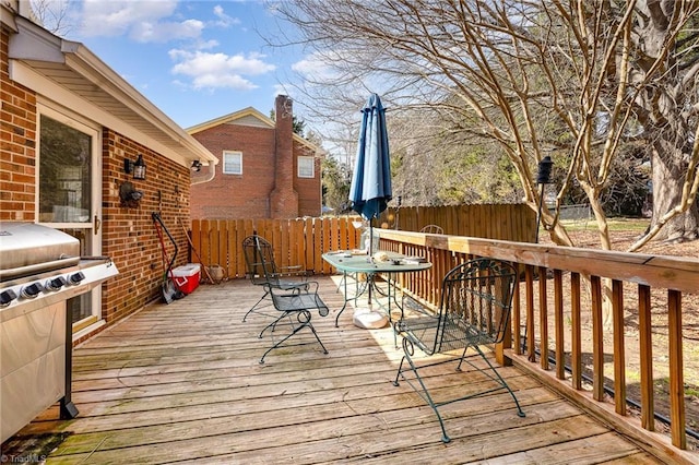 deck featuring a grill, fence, and outdoor dining space