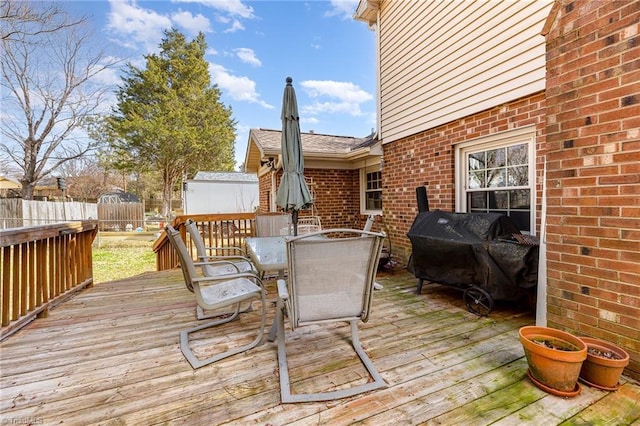 wooden terrace featuring outdoor dining space, a grill, and fence