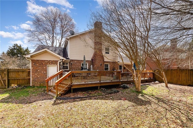 rear view of house featuring brick siding, a chimney, a fenced backyard, and a wooden deck