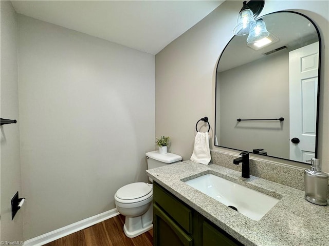 bathroom with vanity, wood finished floors, visible vents, baseboards, and toilet