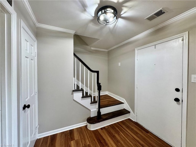 foyer entrance featuring visible vents, crown molding, dark wood-type flooring, baseboards, and stairway