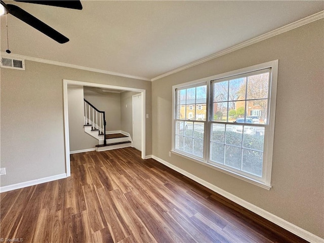 unfurnished room with visible vents, wood finished floors, baseboards, and ornamental molding