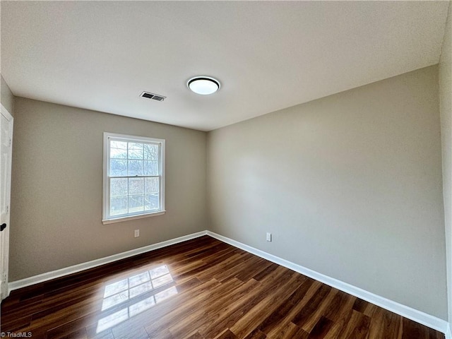 empty room with visible vents, baseboards, and dark wood-style flooring