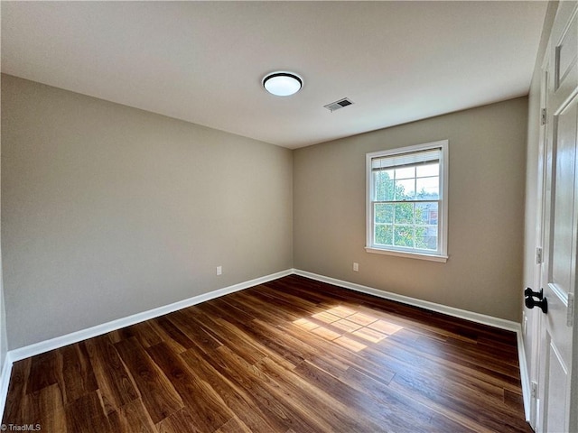 spare room with dark wood-type flooring, baseboards, and visible vents