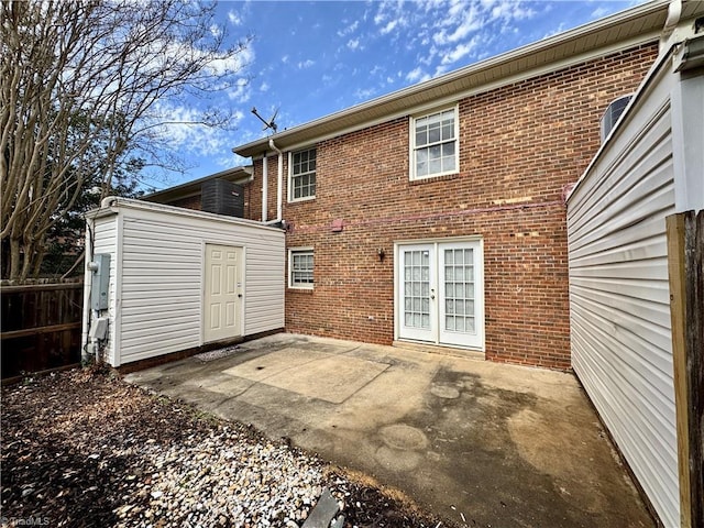 rear view of property featuring french doors, fence, brick siding, and a patio area