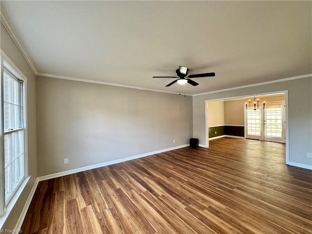 empty room with baseboards, ceiling fan with notable chandelier, wood finished floors, and ornamental molding