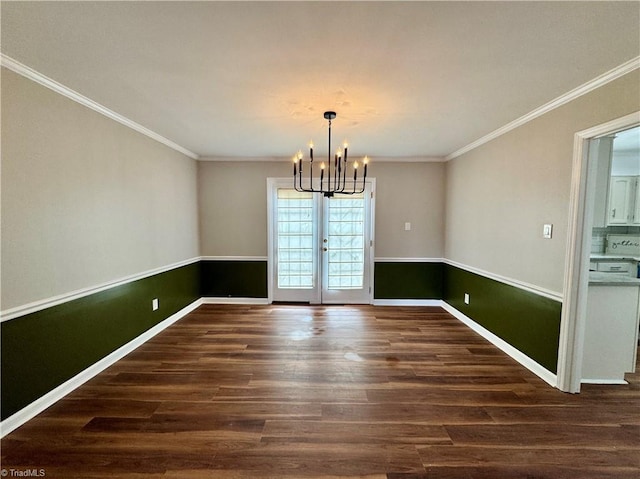 unfurnished dining area with crown molding, a notable chandelier, wood finished floors, and wainscoting