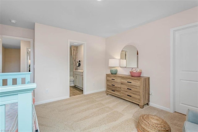 bedroom featuring ensuite bathroom, light carpet, and a crib