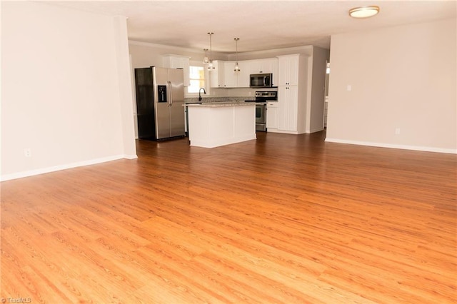 unfurnished living room featuring wood finished floors, baseboards, and a sink