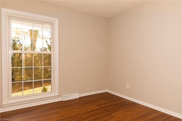 unfurnished room with dark wood finished floors and baseboards