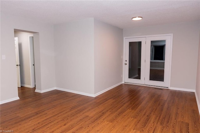 empty room featuring a textured ceiling and dark hardwood / wood-style floors