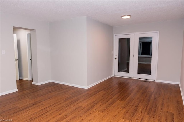 empty room with wood finished floors, a textured ceiling, and baseboards
