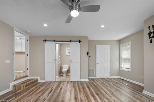 207 Bingham St, Carthage, NC 28327 - unfurnished bedroom featuring light wood-style flooring, a barn door, baseboards, recessed lighting, and connected bathroom